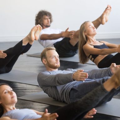Group of young sporty people in Paripurna Navasana pose